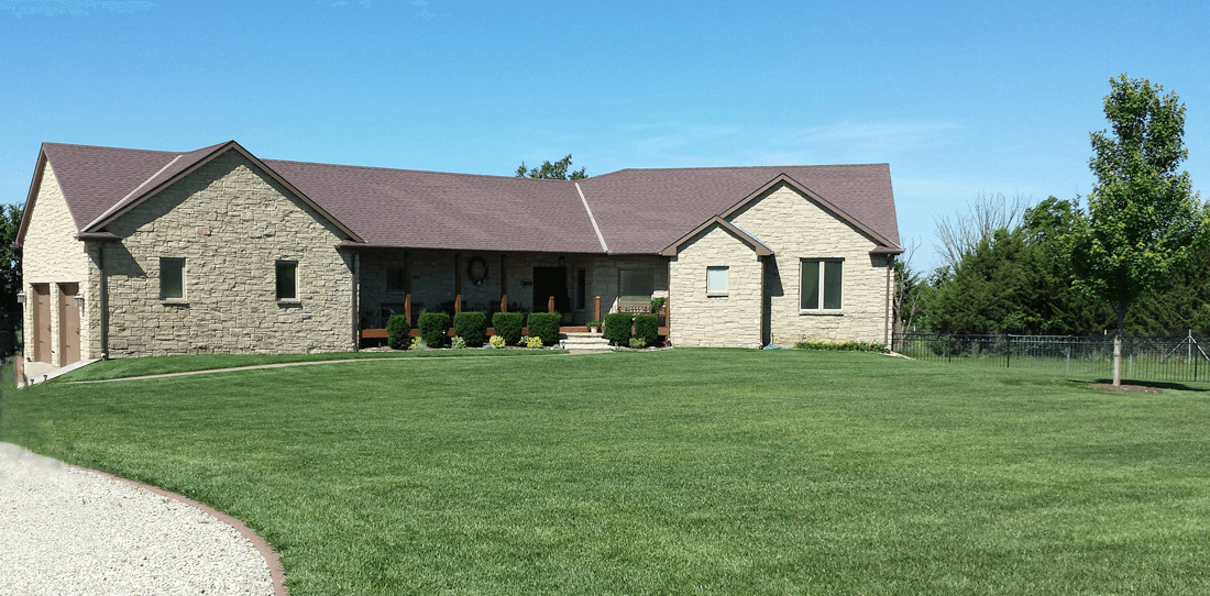 A large, green lawn with a stone home in the background